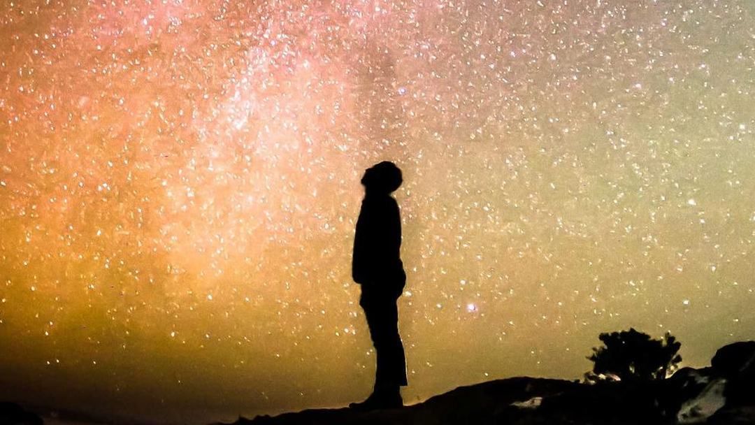 A person standing under the Milky Way
